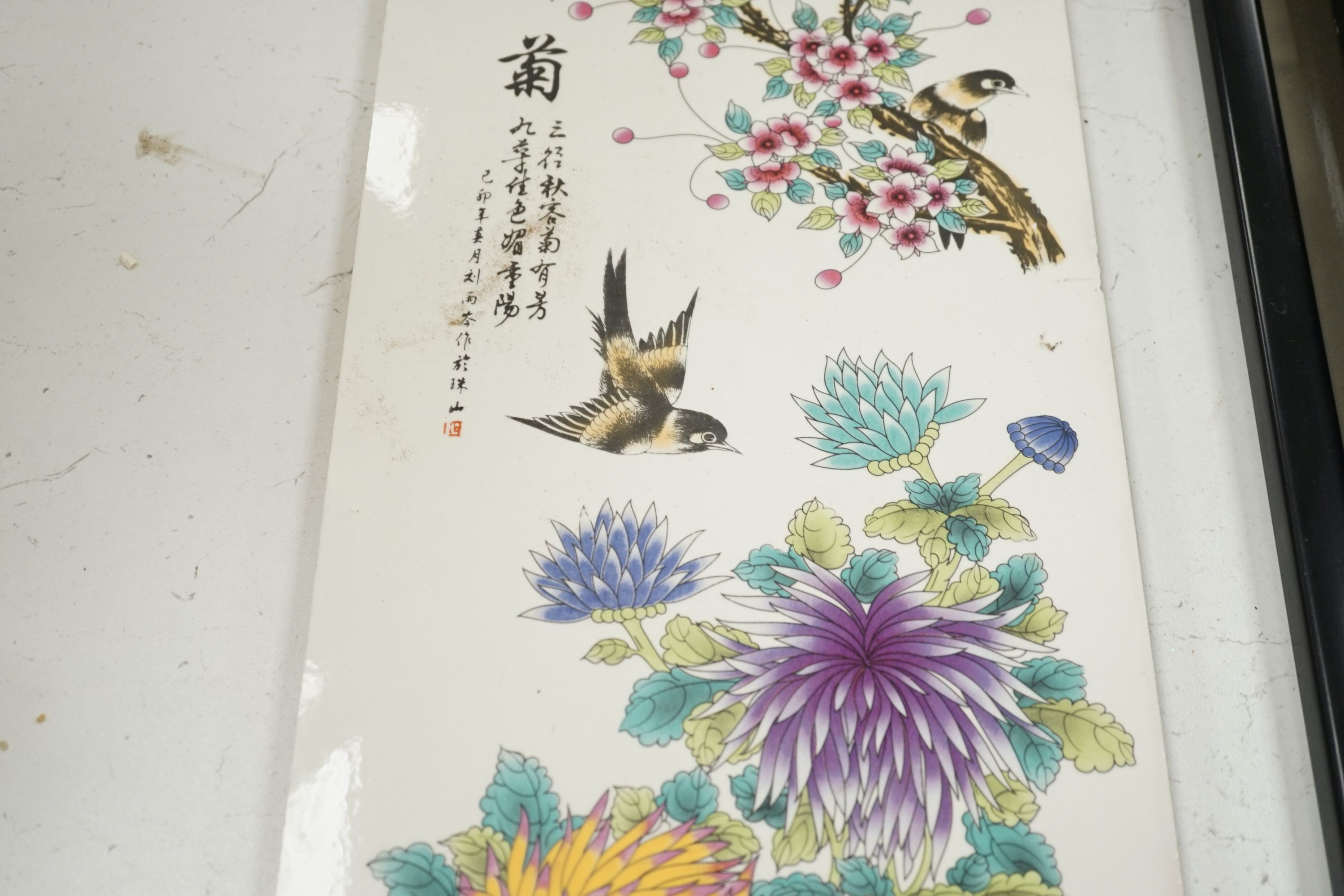 A Chinese enamelled tile, decorated with birds and flowers, 75 cms high x 22 cms wide.
